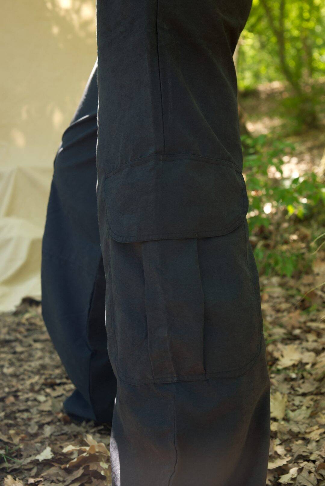 Dark pants worn by a person in a natural outdoor setting with greenery.