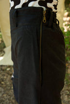 Close-up of dark pants with a zipper, worn over a cow print top.