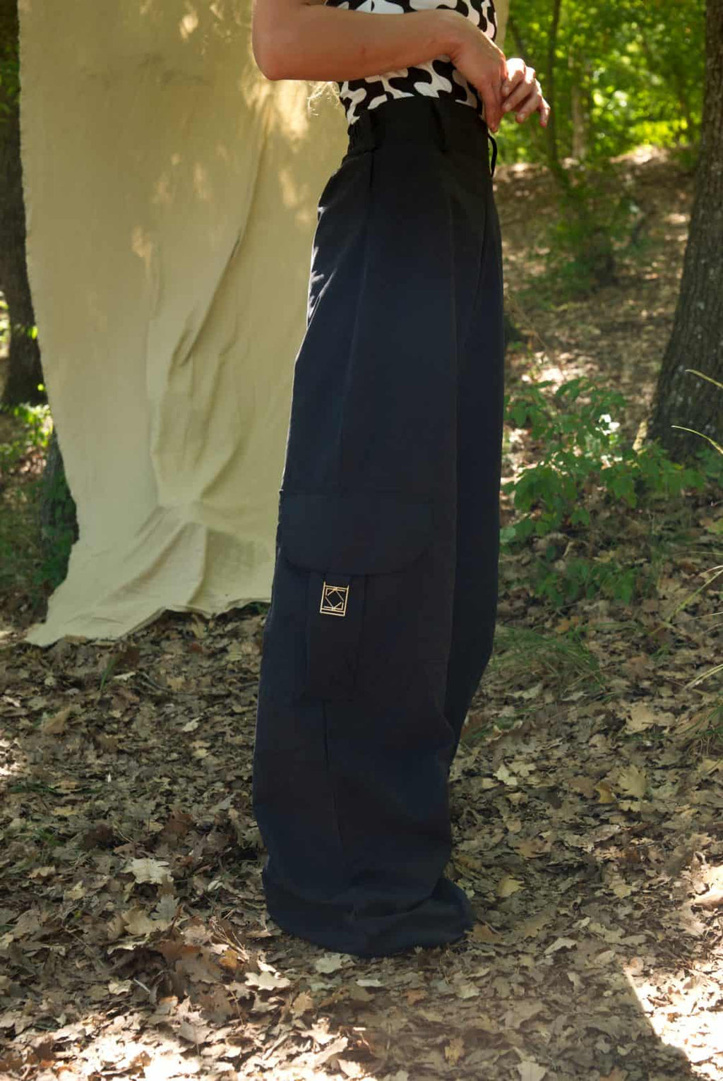 Person wearing navy cargo pants standing in a natural setting with trees and foliage.