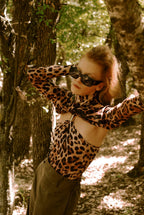 Person wearing a leopard print outfit in a forest setting