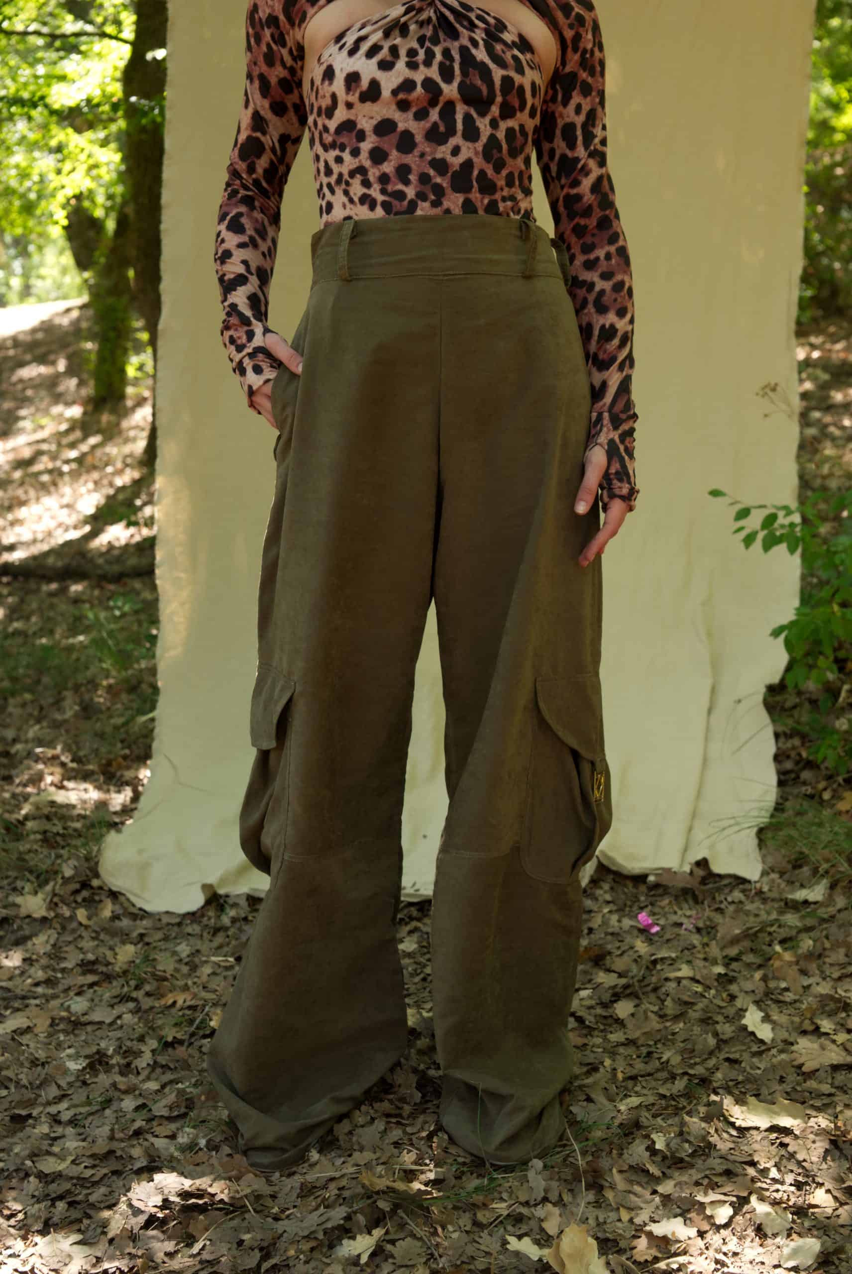 Person wearing a leopard print top and olive green wide-leg pants standing in a natural setting.