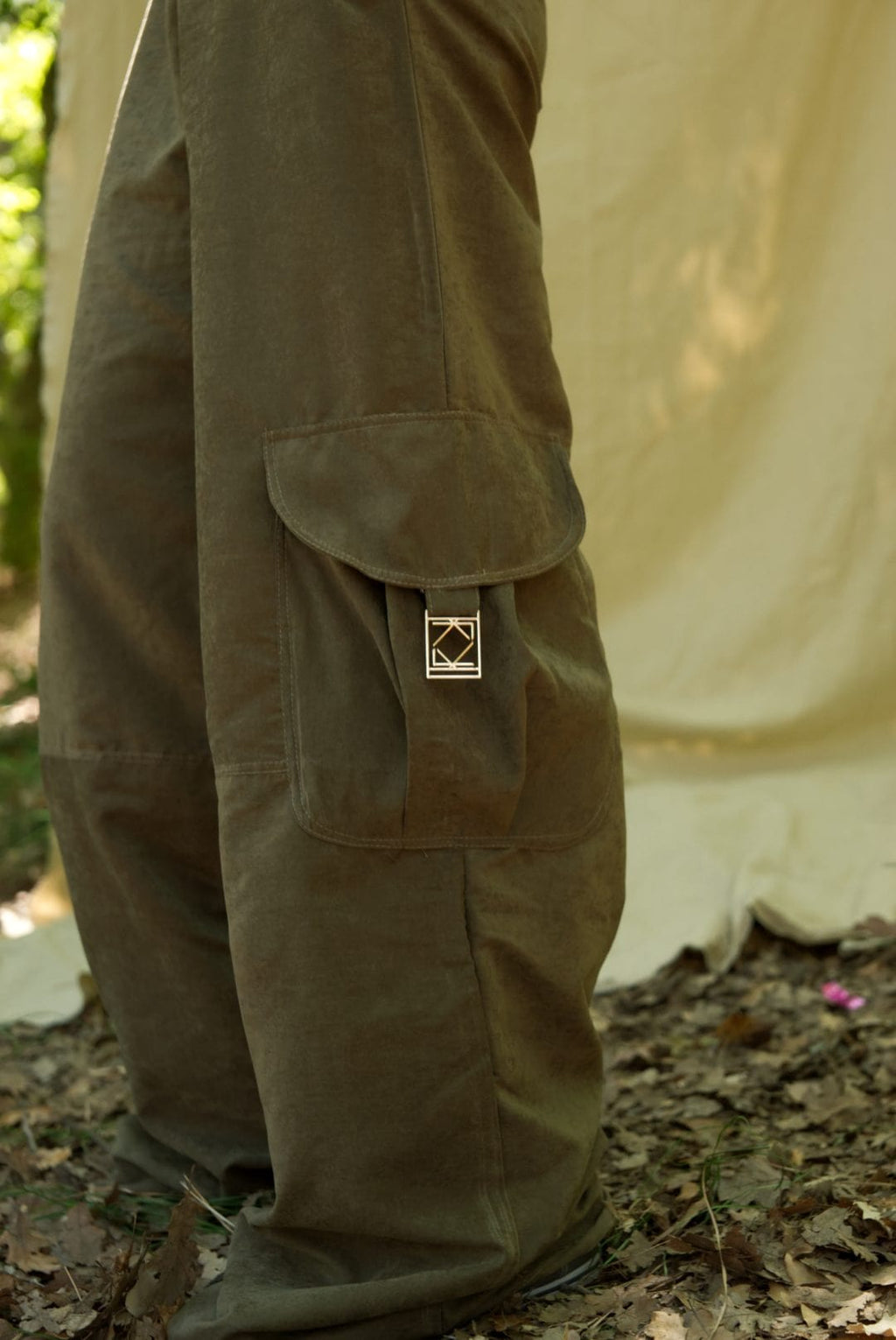 Brown pants with a logo patch on a natural background