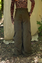 Person wearing a leopard print top and olive green wide-leg pants standing in a natural setting.