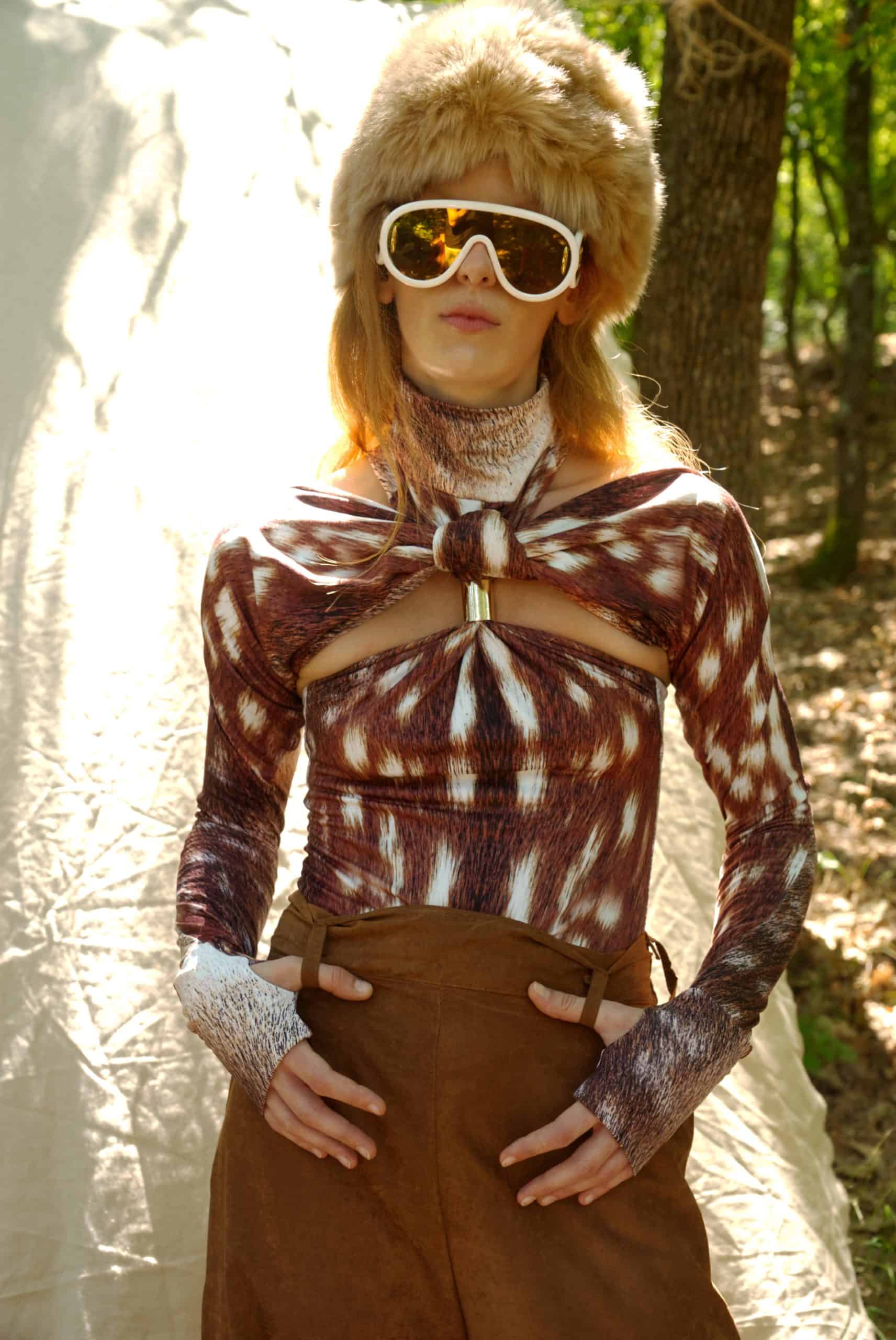 Person wearing a patterned top and fur hat in a forest setting