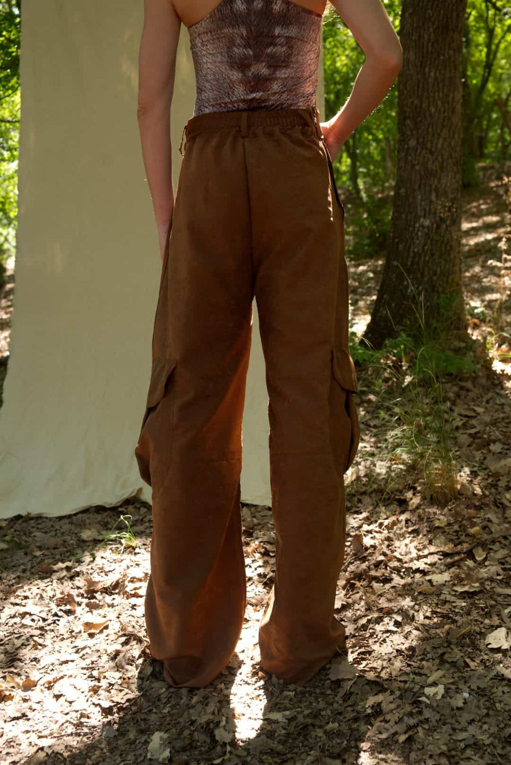 Person wearing brown cargo pants and a patterned top outdoors.