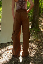 Person wearing brown cargo pants and a patterned top outdoors.