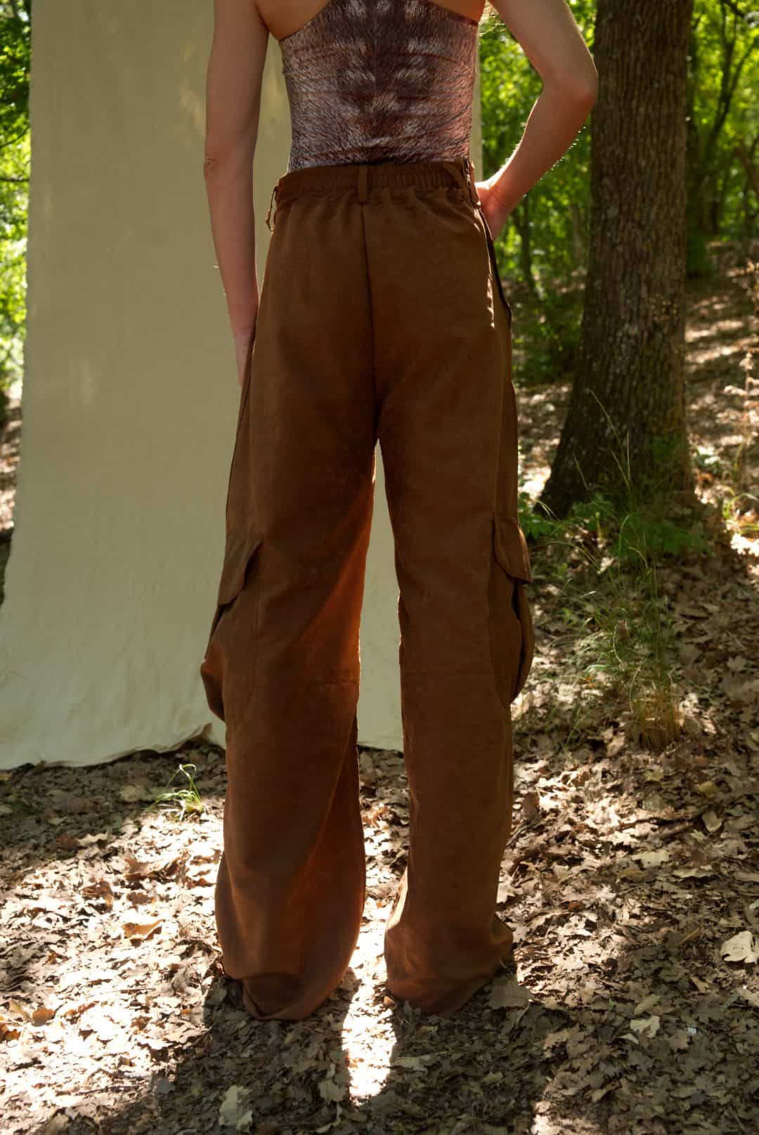 Person wearing brown cargo pants and a patterned top outdoors.