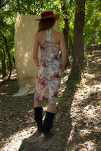 Woman in a patterned dress and hat standing in a forest