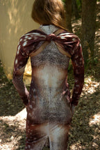Person wearing a long-sleeve dress with a unique pattern outdoors.