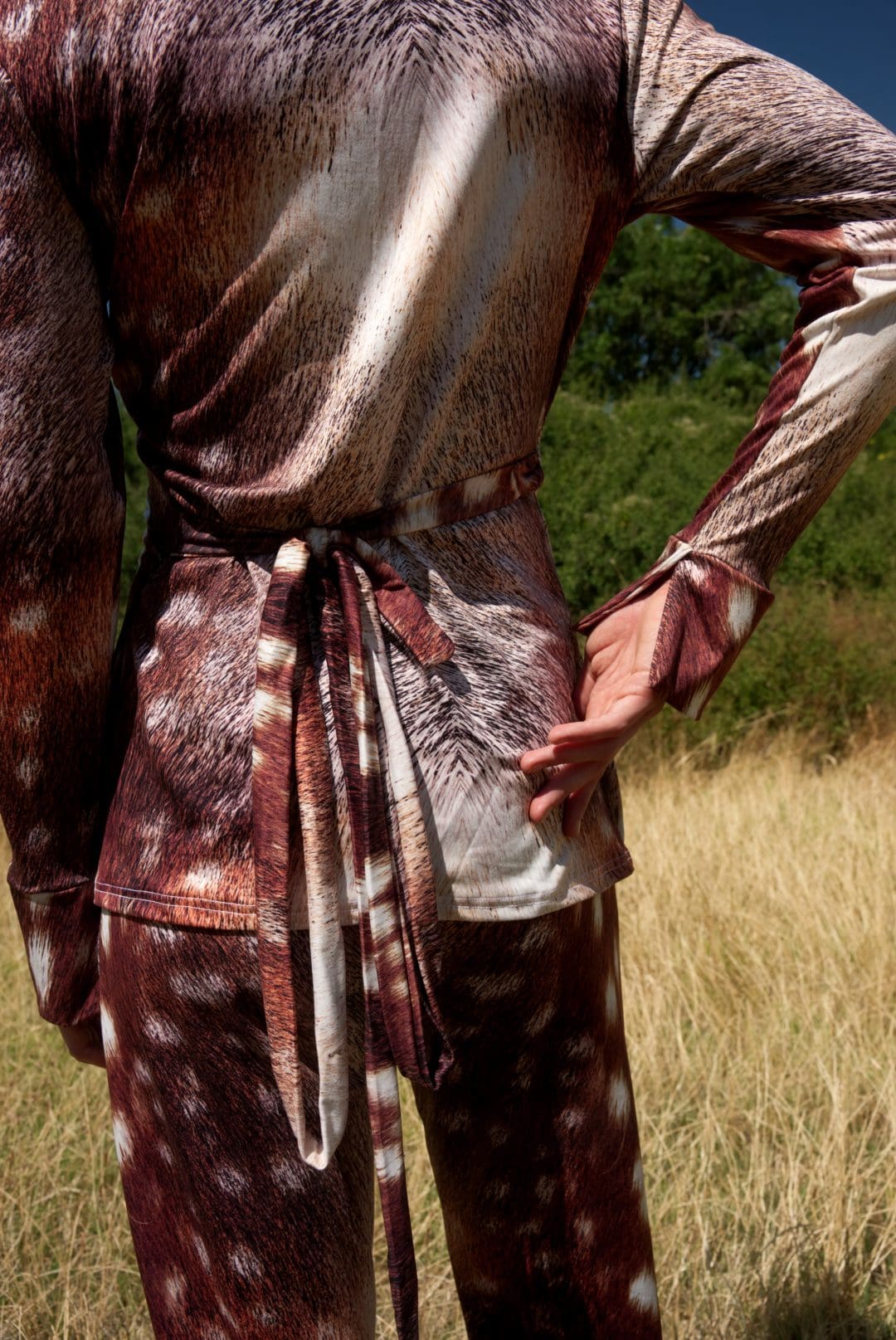 Person wearing a patterned outfit with a belt in a natural setting