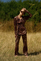 Person wearing a leopard print outfit standing in a field with greenery in the background