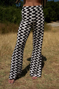 Person wearing black and white patterned pants standing in a grassy outdoor area.