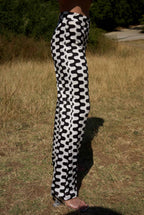 Person wearing black and white patterned pants standing in a grassy area.
