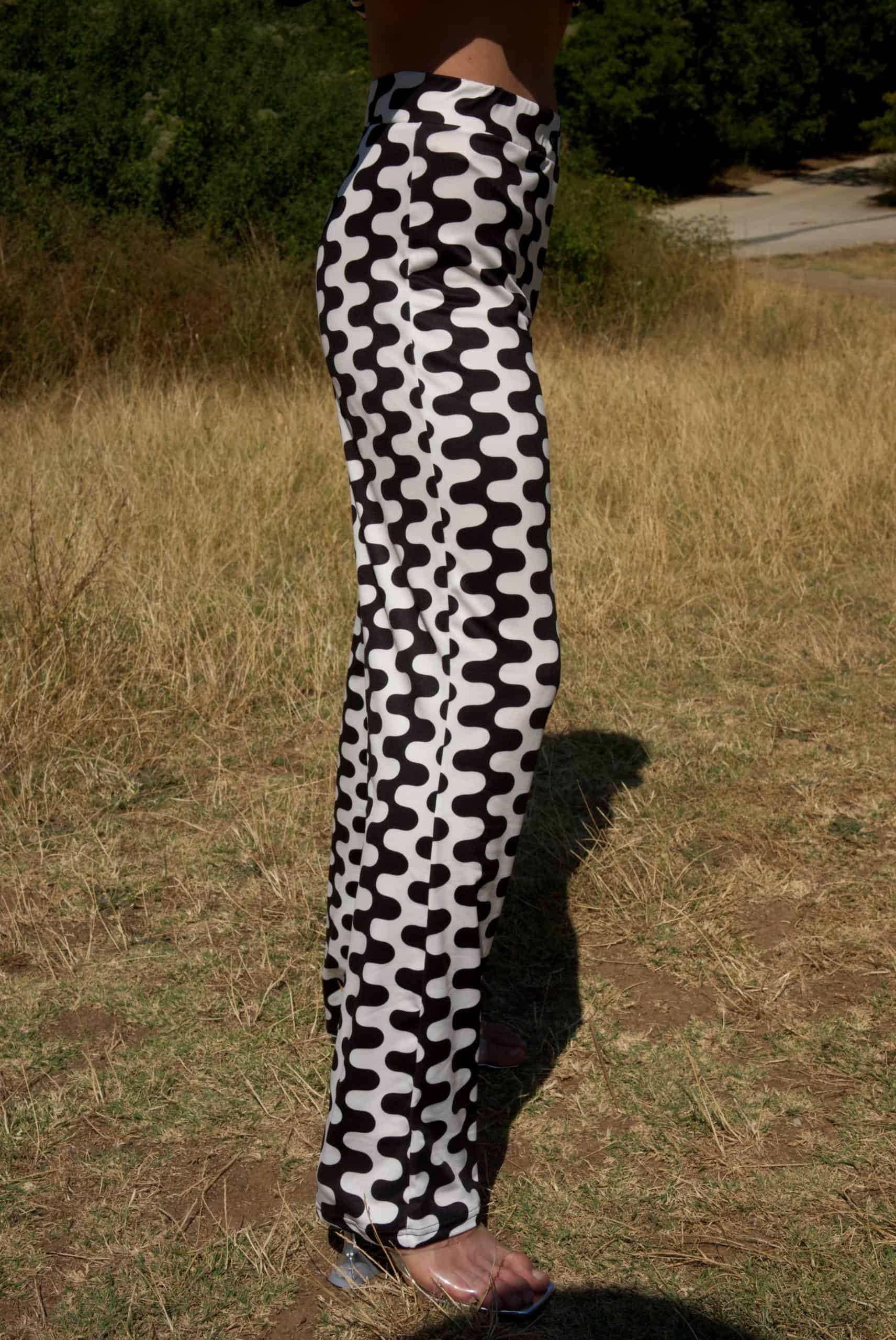 Person wearing black and white patterned pants standing in a grassy area.