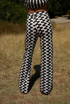 Person wearing black and white patterned pants standing in a grassy field.