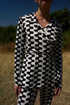 Person wearing a black and white patterned outfit standing in a field.