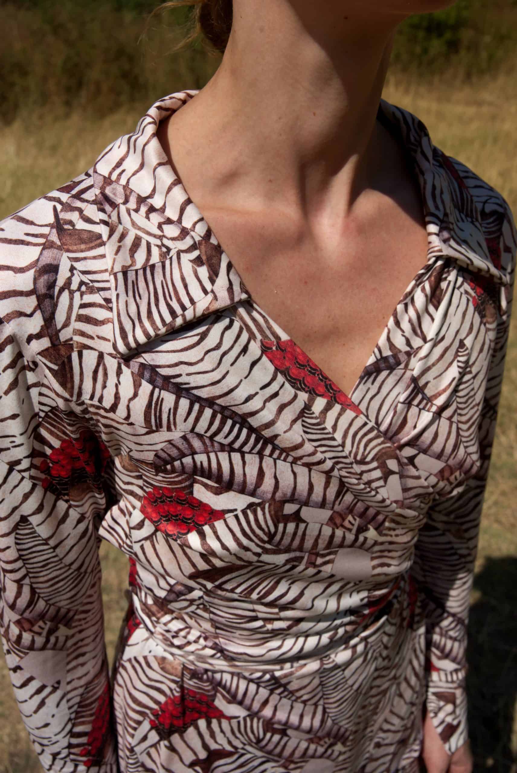 Person wearing a patterned dress with zebra and red accents in an outdoor setting