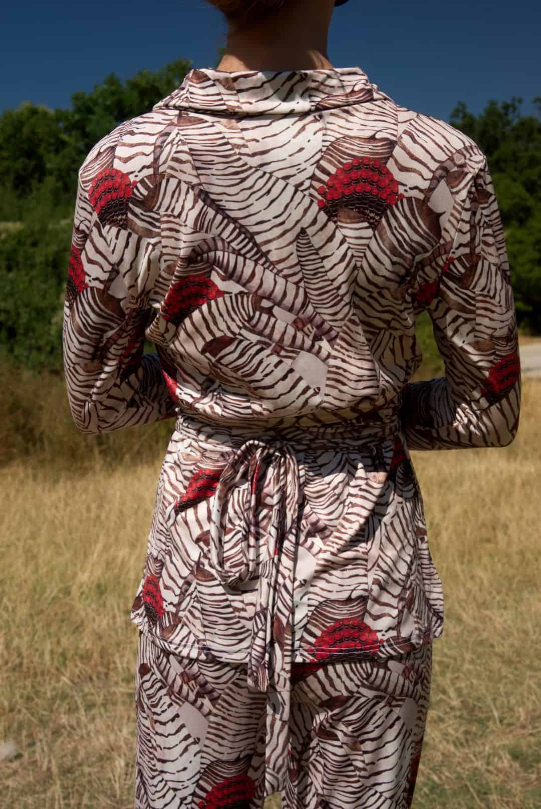 Person wearing a patterned outfit with red and black designs in an outdoor setting.