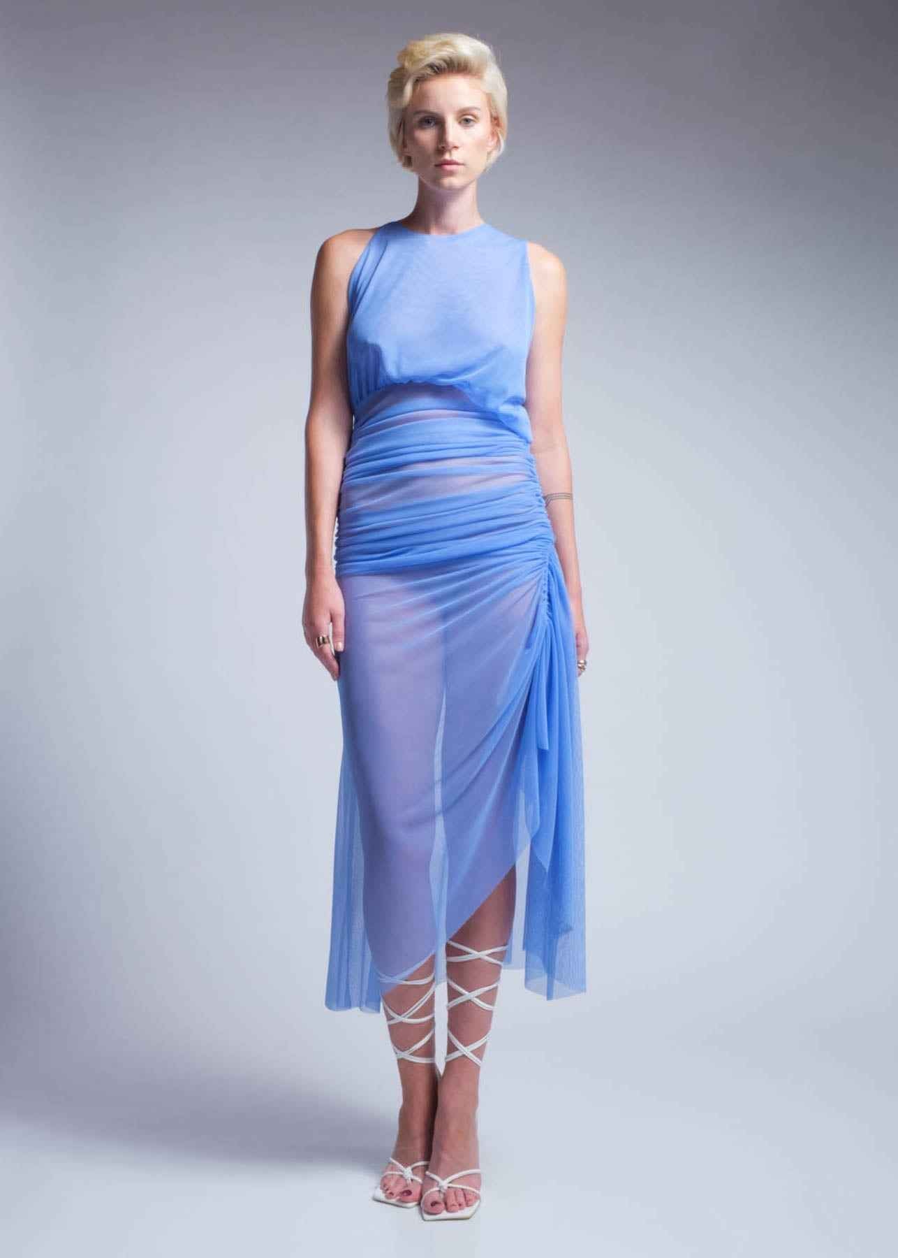 Woman wearing a blue dress with sheer overlay on a gray background