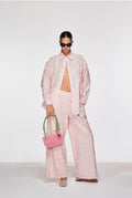 Person wearing a pink outfit with sunglasses and a handbag on a white background