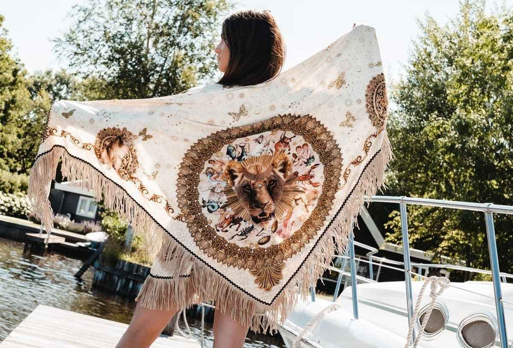 Woman holding a decorative shawl with tigers on a dock by a lake