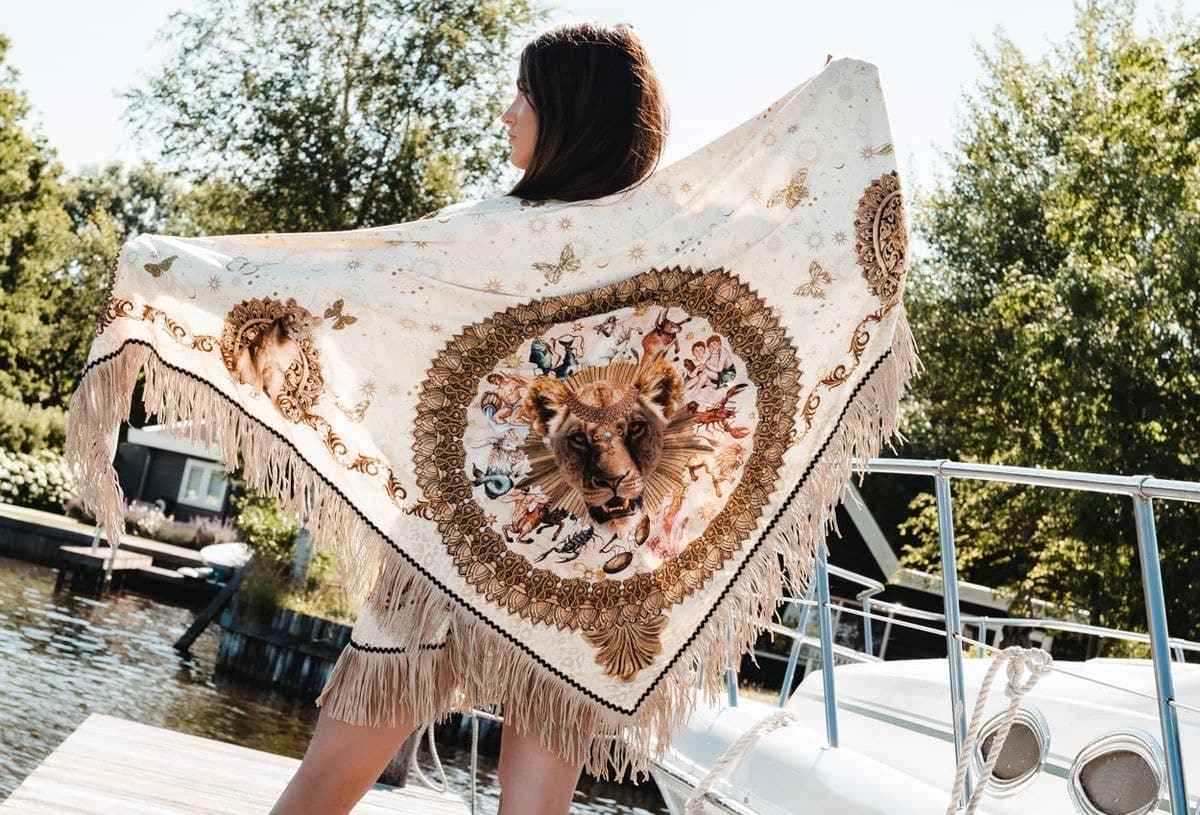 Woman holding a decorative shawl with tigers on a dock by a lake