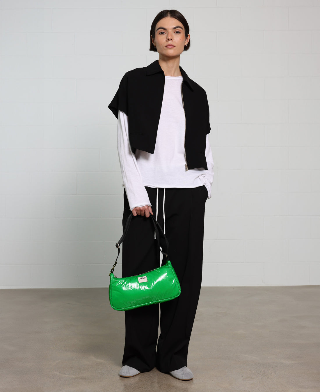 Person holding a green handbag against a plain background