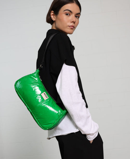 Person wearing a black and white jacket with a green bag on a gray background