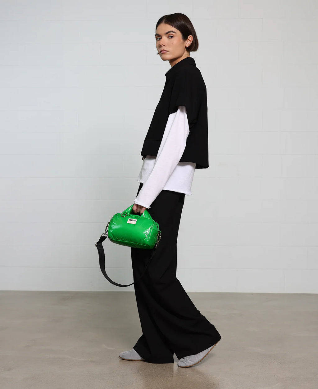 Person holding a green handbag against a plain background