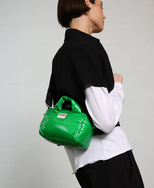 Person holding a green puffer bag against a plain background