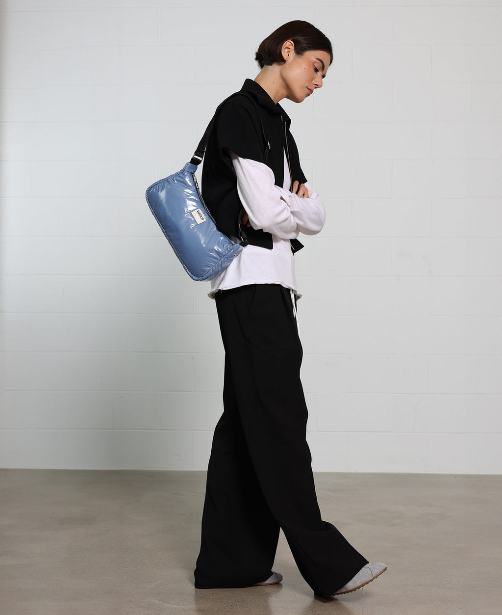 Person holding a blue cylindrical bag against a plain background