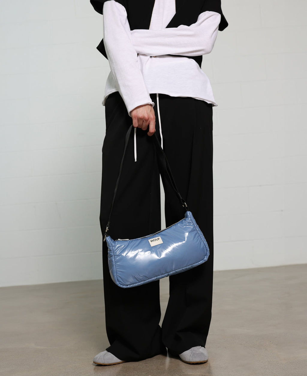 Person holding a blue shiny handbag against a plain background