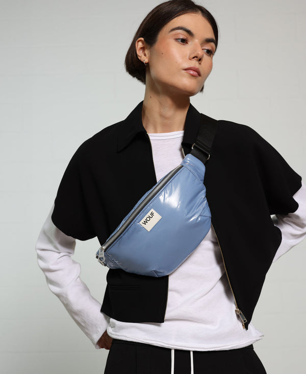Person wearing a blue waist bag with a neutral background