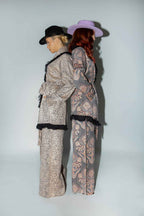 Two people in patterned outfits standing back-to-back against a white background