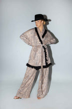 Person wearing a sparkly outfit with black trim and a hat on a plain background