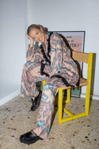 Person wearing a patterned outfit sitting on a chair with a yellow frame.