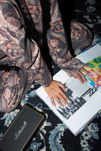 Person with tattoos holding a book on a patterned surface