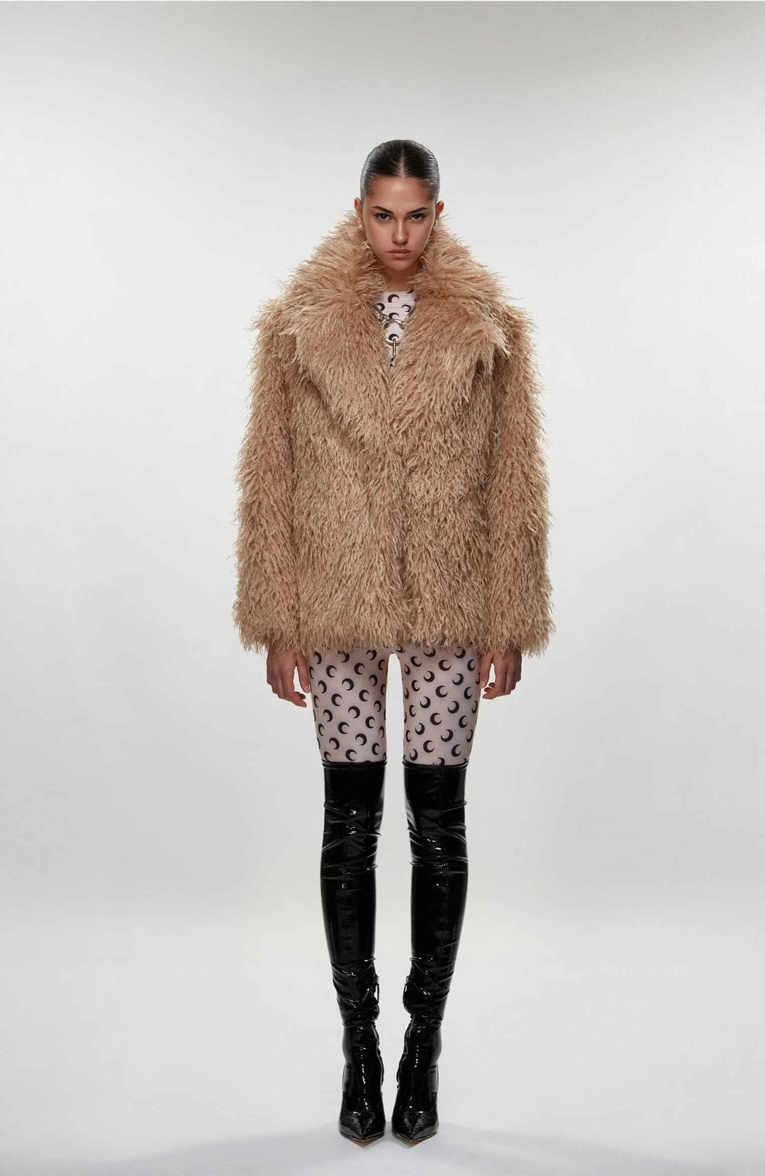 Person wearing a fluffy beige coat on a white background