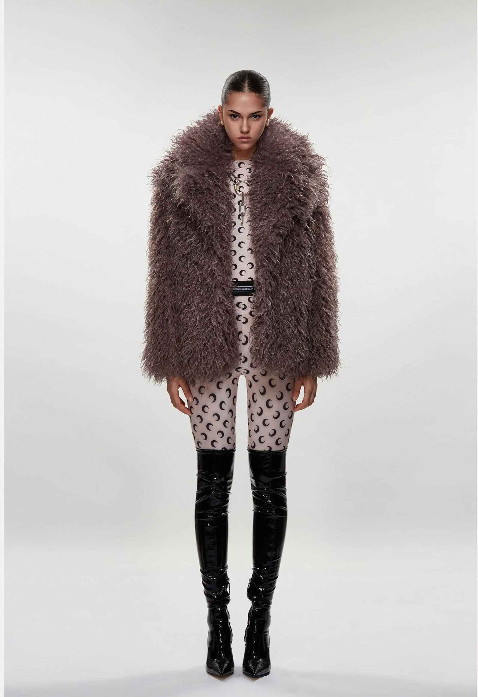 Person wearing a fur coat, patterned outfit, and black boots on a white background