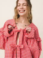 Woman wearing a red and white checkered blouse with a neutral background