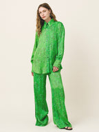 Woman wearing a green patterned outfit on a beige background