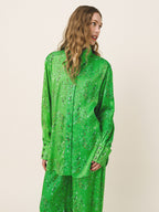 Woman wearing a green patterned outfit against a beige background