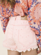 Person wearing a floral blouse and pink denim shorts with Levi's branding.