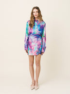 Woman wearing a colorful tie-dye dress on a beige background