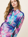 Woman wearing a colorful tie-dye shirt against a plain background