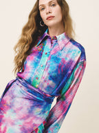 Woman wearing a colorful tie-dye shirt against a plain background