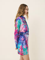 Woman wearing a colorful tie-dye dress on a plain background