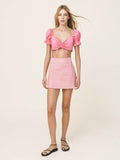 Woman wearing a pink top and skirt set on a plain background