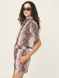 Woman wearing a leopard print outfit with sunglasses on a plain background