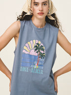 Woman wearing a blue sleeveless shirt with a palm tree and sunset design.